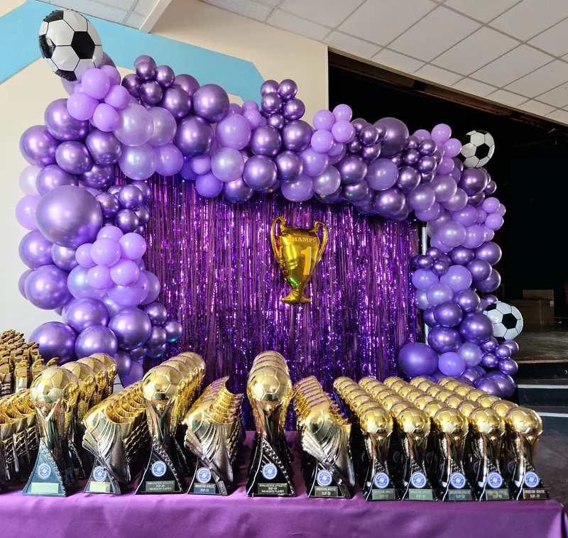 Fioletowa ścianka balonowa i statuetki na sportowej gali