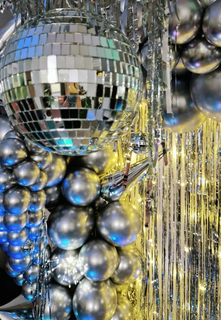 Kula dyskotekowa i srebrne balony z błyszczącą kurtyną