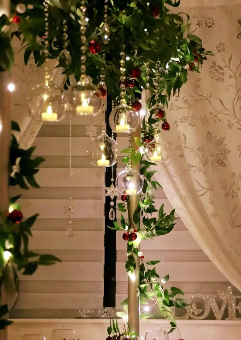 Girlanda z zieleni i wiszących lampionów przy oknie