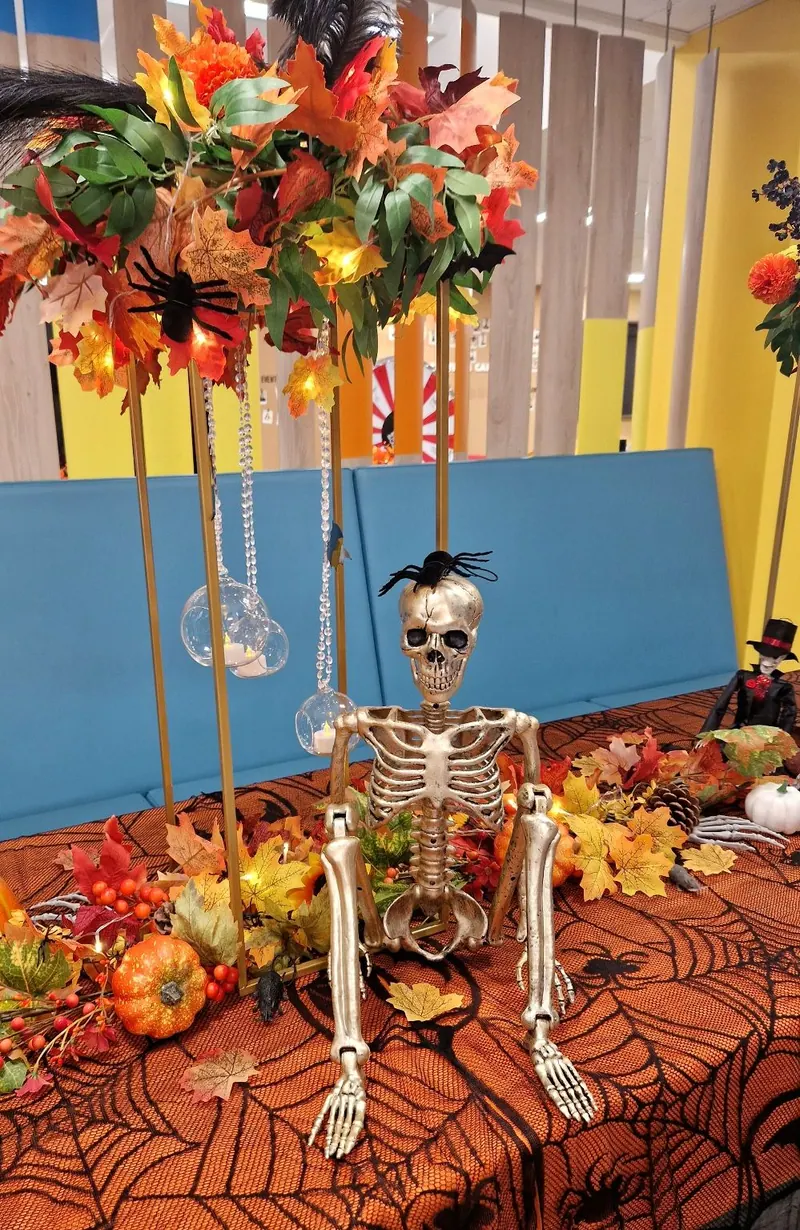 Halloweenowa dekoracja stołu z kościotrupem i jesiennymi kwiatami