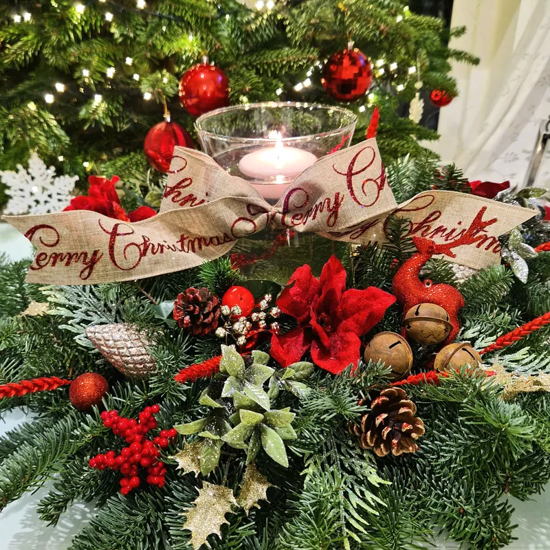 Świąteczny stroik z czerwonymi kwiatami, szyszkami i wstążką „Merry Christmas”