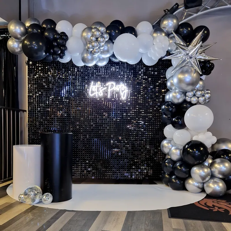 Czarna ścianka cekinowa z neonem „Let’s Party” i czarno-srebrnymi balonami