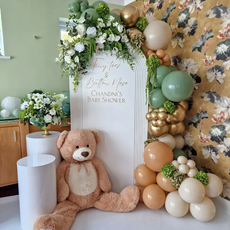 Dekoracja na baby shower z zielono-beżowymi balonami, kwiatami i misiem