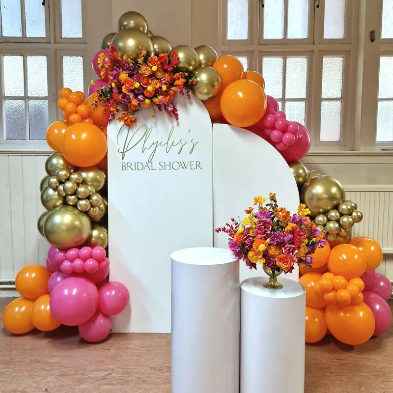 Dekoracja na bridal shower z pomarańczowo-różowymi balonami i kwiatami