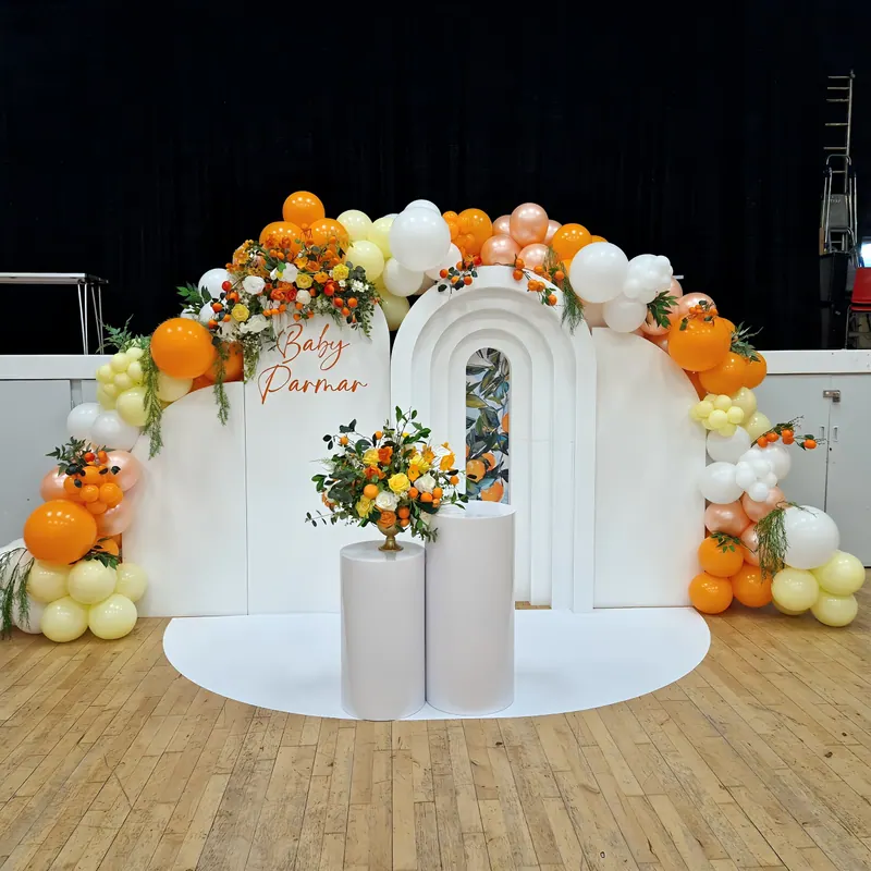 Dekoracja na baby shower z pomarańczowo-białą girlandą balonową i kwiatami